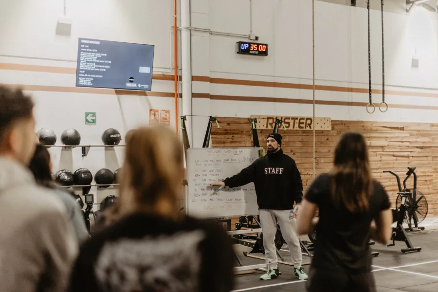 Coach explaining the WOD on the whiteboard with athletes listening