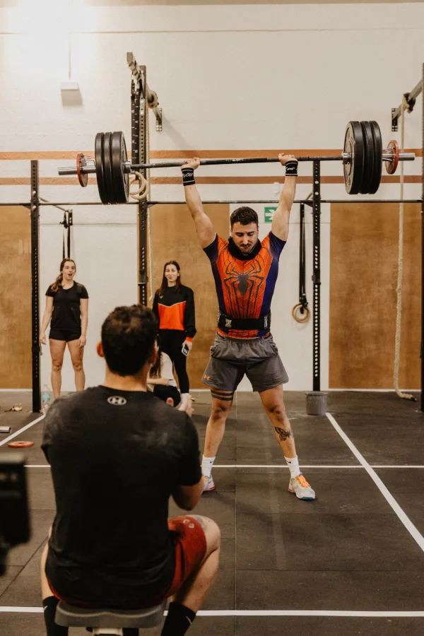 Athlete doing weightlifting with barbell overhead at the box