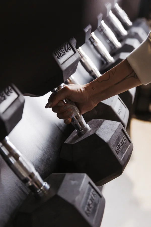 Detall de mà agafant dumbell Ruster al rack d'equipament