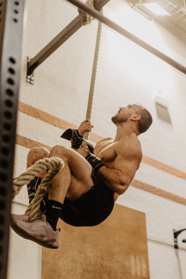 Athlete doing rope climb at CrossFit La Mola, like climbing La Mola step by step